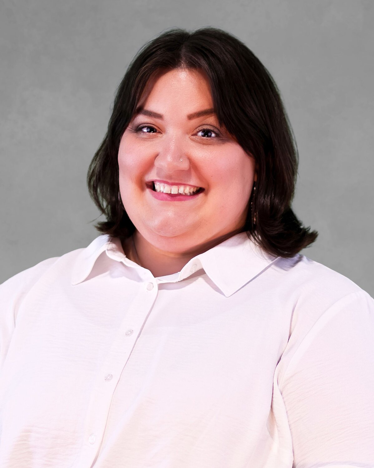 Person wearing a white button-up shirt against a plain gray background.