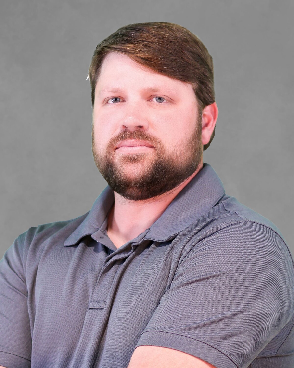 Person wearing a gray polo shirt standing with arms crossed against a plain gray background.